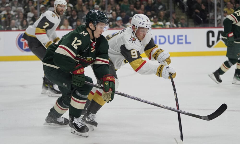 Minnesota Wild left wing Matt Boldy (12) and Vegas Golden Knights center Jack Eichel (9) battle for the puck during the first period of Game 3 of a first-round NHL hockey playoff series Thursday, April 24, 2025, in St. Paul, Minn. (AP Photo/Abbie Parr)